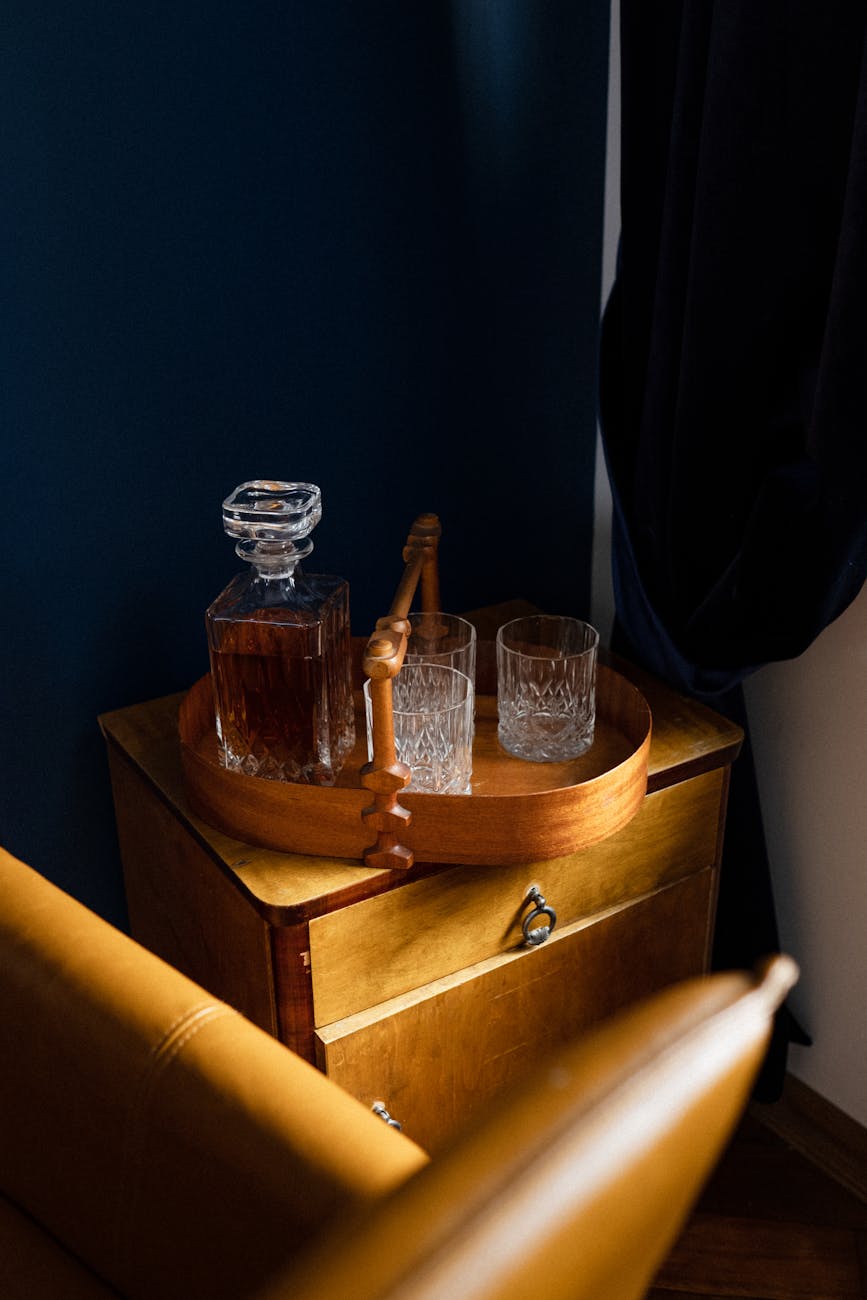 A stylish home bar with a crystal whiskey decanter and glasses on a wooden tray.