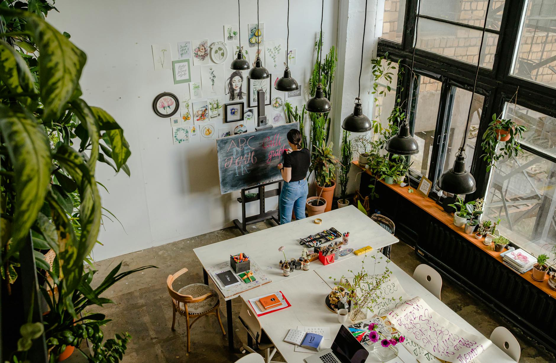 Aerial view of a creative workspace with art supplies and plants, promoting creativity and greenery.