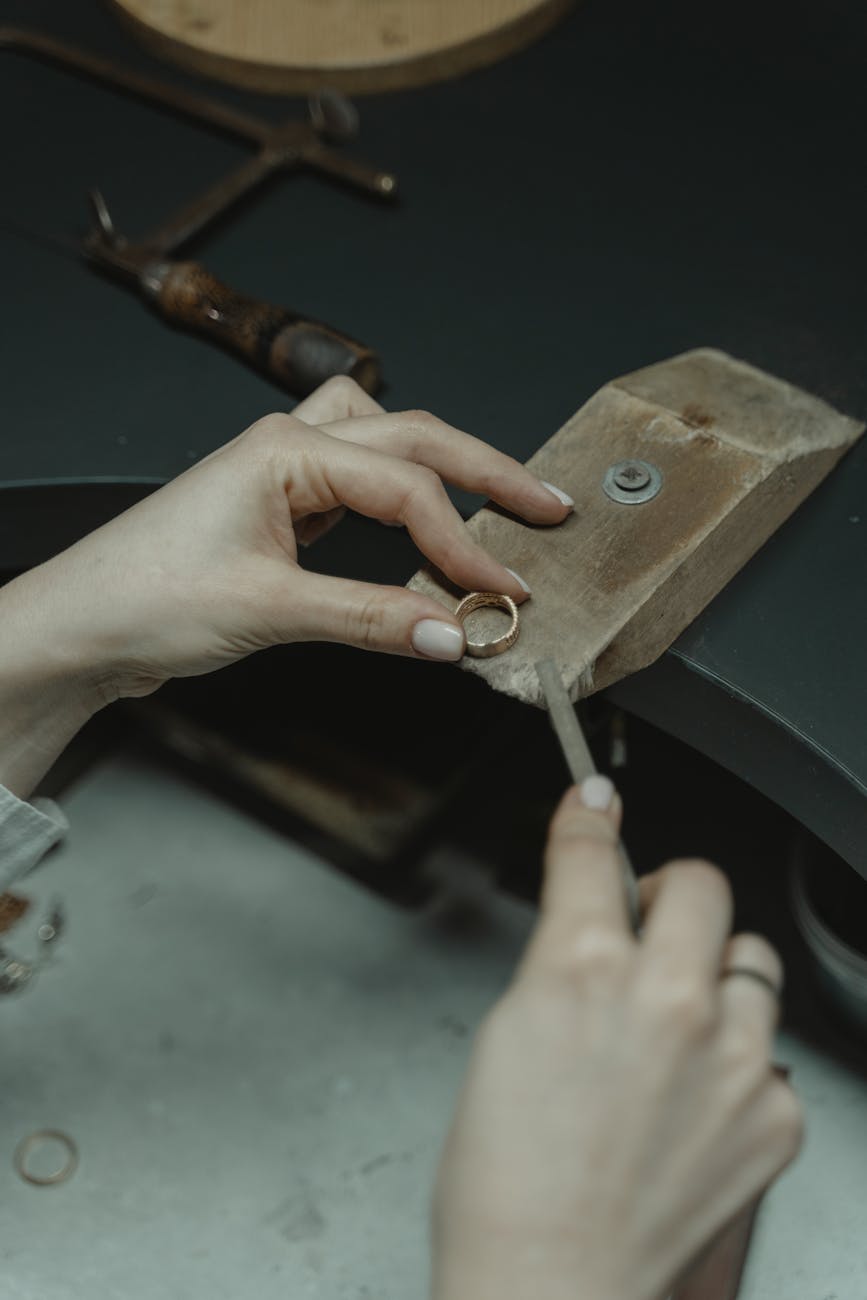 Close-up of a jeweler using hand tools to craft a gold ring in an artisan workshop.