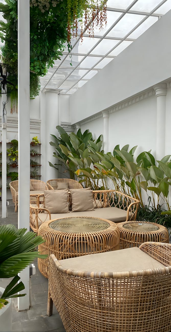 Relaxing indoor garden patio with wicker furniture and lush plants.