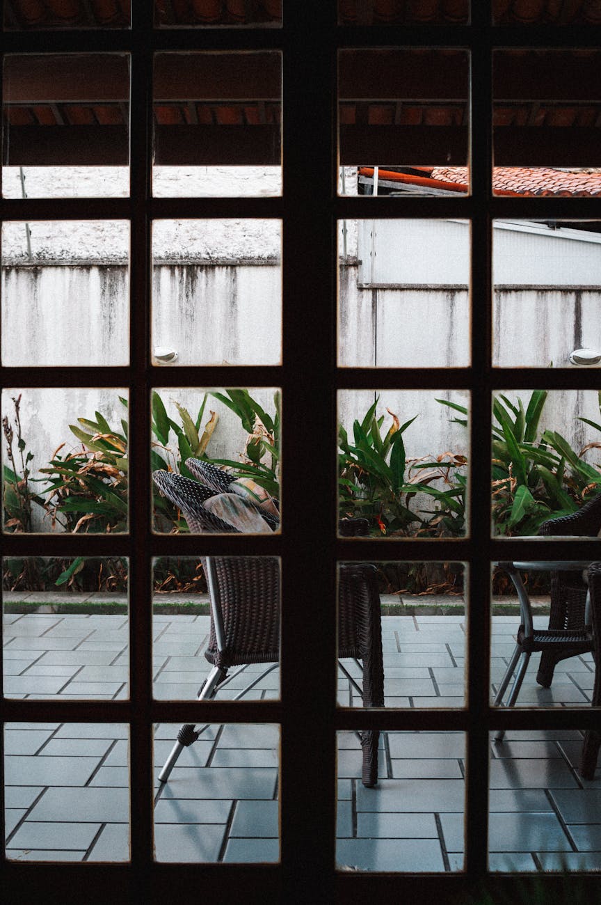 A tranquil outdoor patio observed through a window grid, perfect for leisure and relaxation.