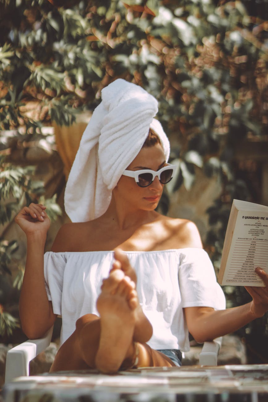 A stylish woman reads outdoors in summer, exuding elegance and leisure.