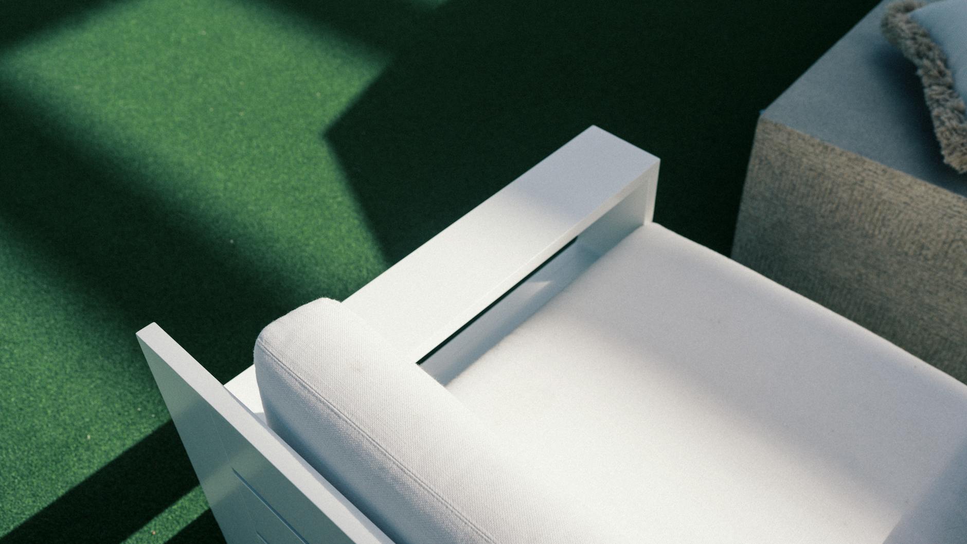 Minimalist white patio chair on green turf in sunlight. Perfect for modern outdoor decor.