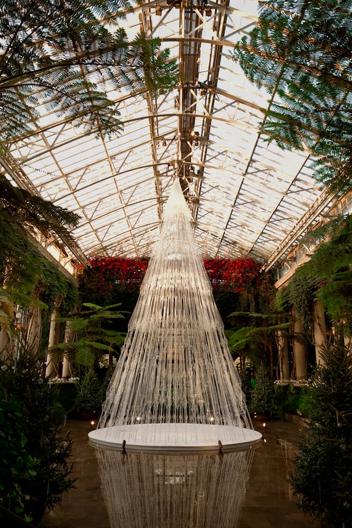A grand hanging art installation envelops the elegant conservatory interior with lush greenery.