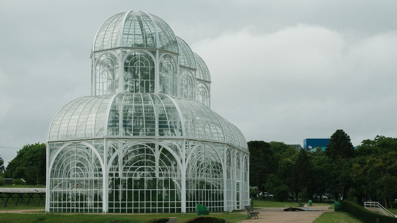 why-choose-us Elegant glass conservatory amidst a green park, showcasing modern architectural design.