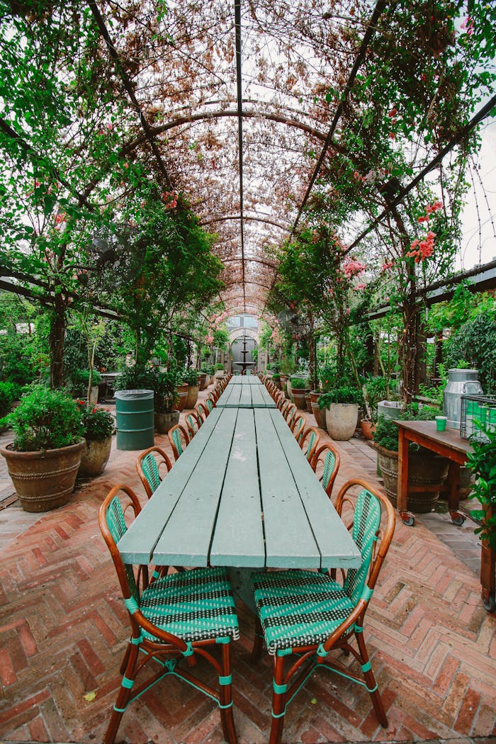 services-04 Long table under a lush floral archway, perfect for outdoor dining in a serene garden setting.