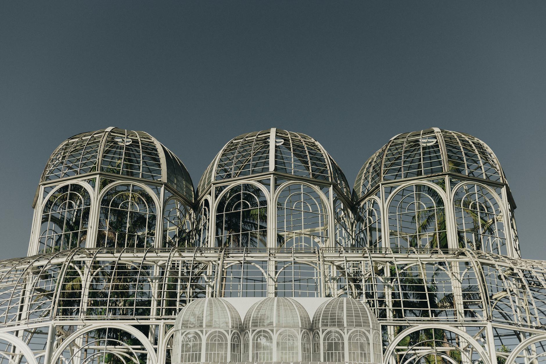 Modern greenhouse with steel and glass structure against a clear sky. Iconic architectural design.