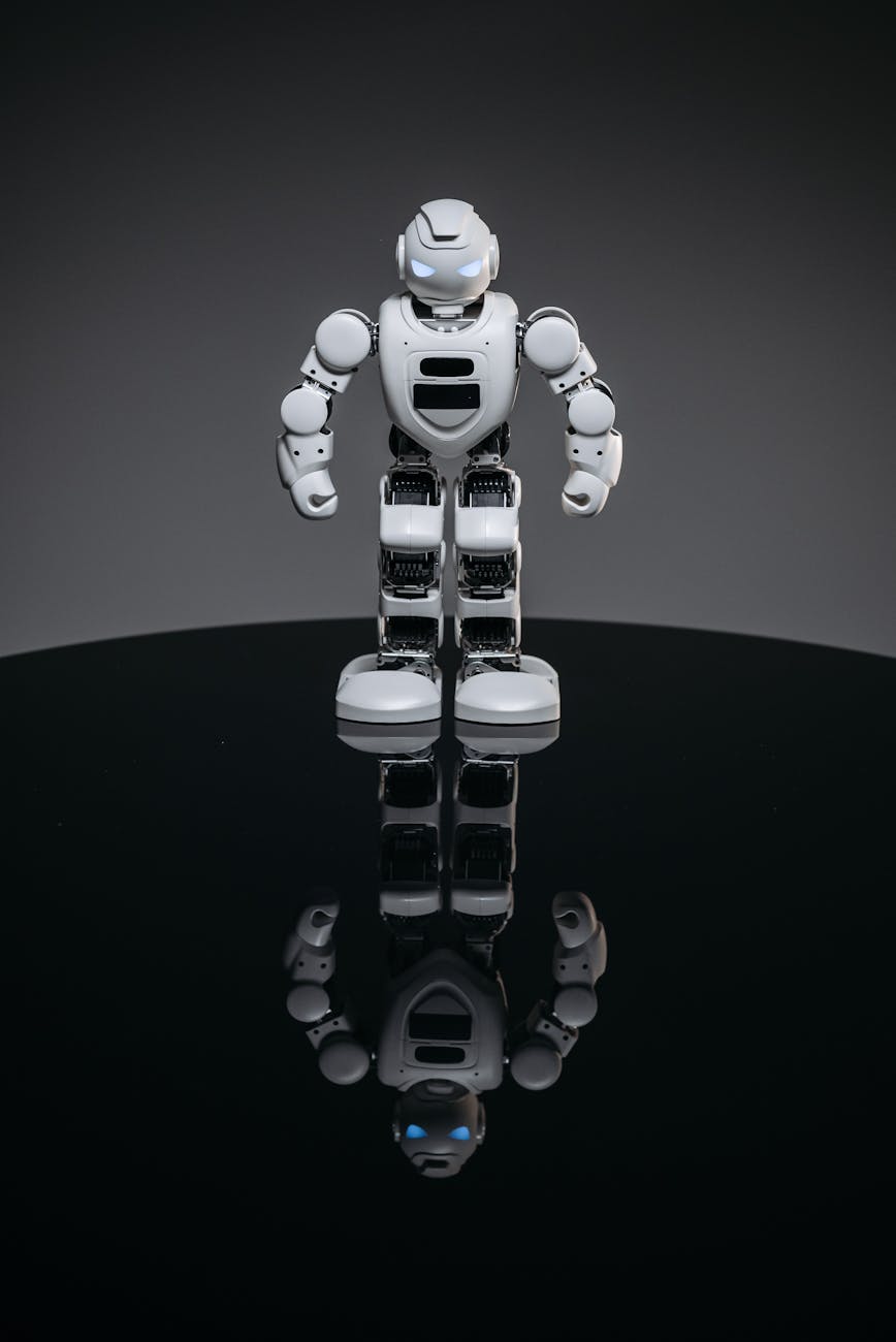 A modern robot with glowing eyes standing and reflecting on a glossy surface.
