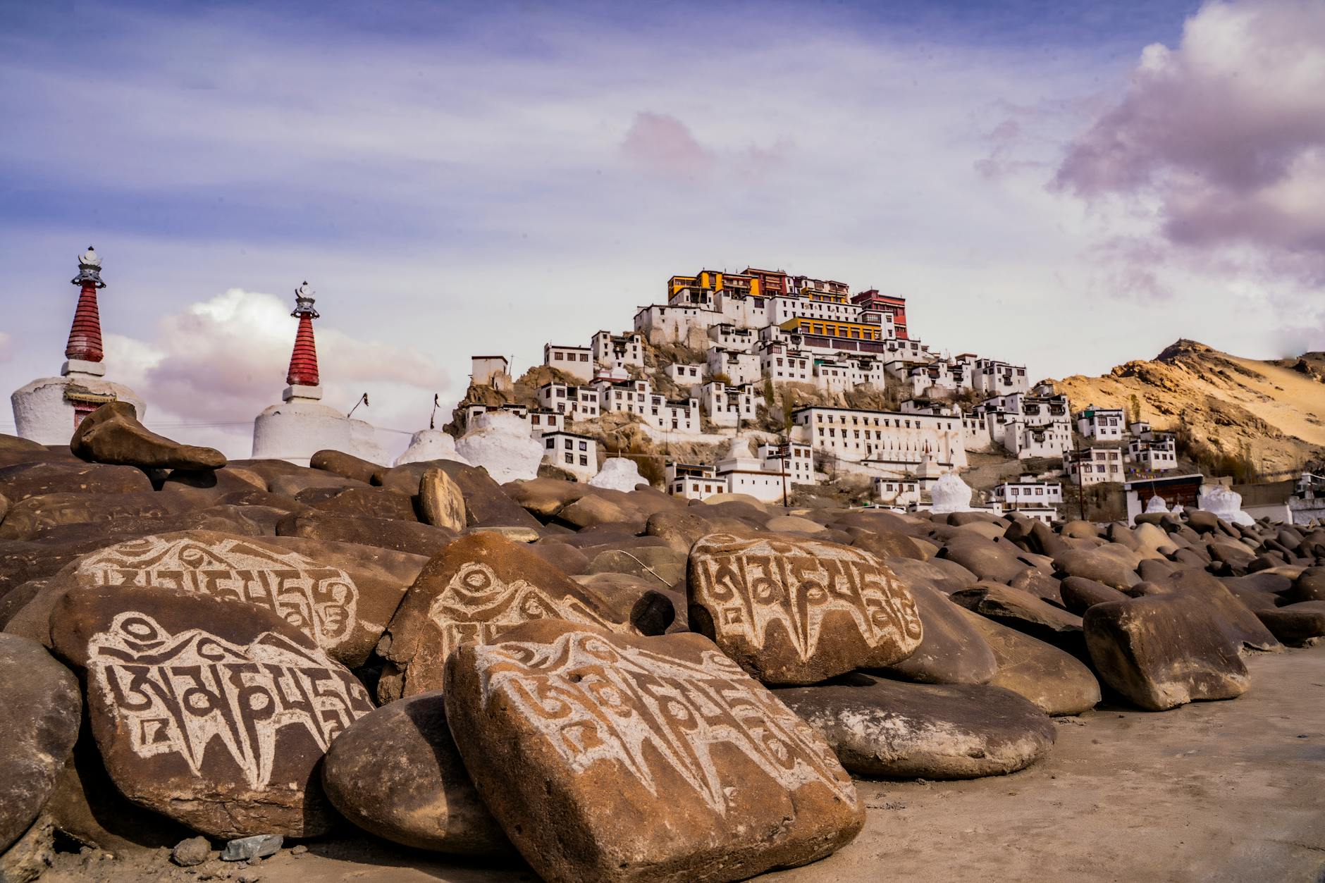 Dramatic view of a Tibetan monastery surrounded by sacred mani stones in Ladakh, India.